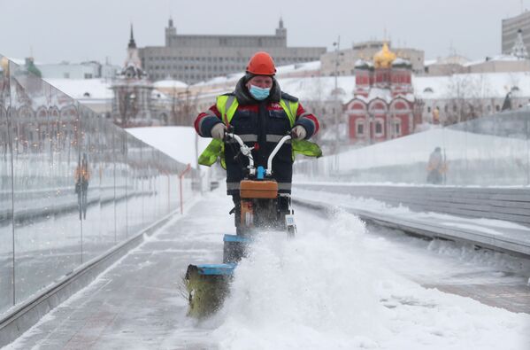عامل يقوم بتنظيف أحد ممرات جسر بارياشي في حديقة زارياديه في موسكو، 14 يناير 2021 - سبوتنيك عربي