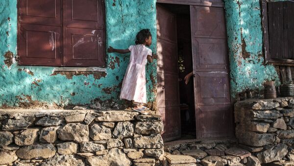 فتاة تنظر داخل منزل بينما يخرج شخص ما يده لها في مدينة جوندر، إثيوبيا، 17 يناير 2021 - سبوتنيك عربي