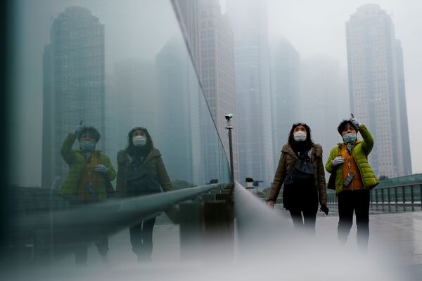 أشخاص يرتدون كمامات يسيرون في أحد الشوارع وسط تفشي مرض فيروس كورونا (كوفيد-19) في شنغهاي الصين، 26 يناير 2021 - سبوتنيك عربي