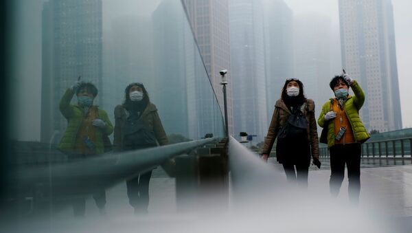 أشخاص يرتدون كمامات يسيرون في أحد الشوارع وسط تفشي مرض فيروس كورونا (كوفيد-19) في شنغهاي الصين، 26 يناير 2021 - سبوتنيك عربي