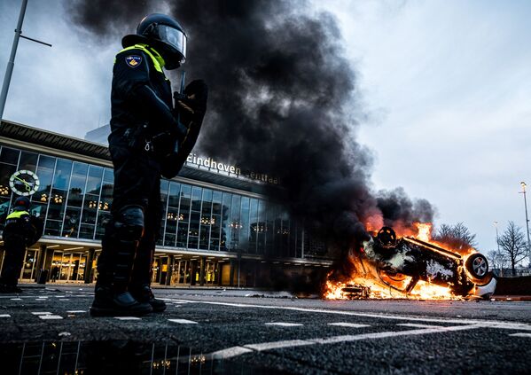 اشتعال النيران في سيارة أمام محطة القطار، بعد احتجاجات من قبل عدة مئات من الأشخاص ضد سياسة كورونا، في أيندهوفن، هولندا 24 يناير 2021  - سبوتنيك عربي