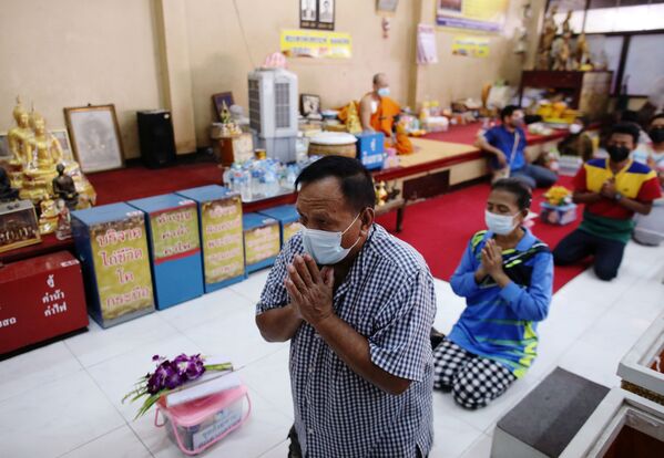 المصلون قبل الدخول إلى التوبيت للصلاة والدعاء لـ خداع الموت وتحسين حظهم في معبد في بانكوك، تايلاند، 27 يناير 2021 - سبوتنيك عربي