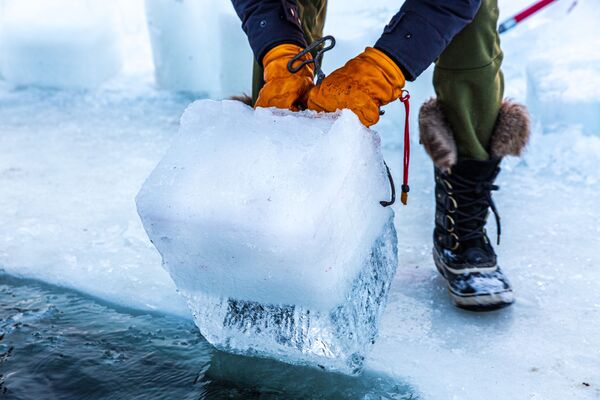 أعضاء مجموعة الغطاسين يقومون بإزالة الجليد من بركة السباحة الباردة درجة حرارة مياهها 37.4 درجة فهرنهايت (3 درجات مئوية)، بعد الغطس في موقع مخصص للسباحة الباردة وسط بحيرة هارييت المتجمدة في مدينة مينيابوليس، ولاة مينيسوتا الأمريكية، في 30 يناير 2021 - سبوتنيك عربي