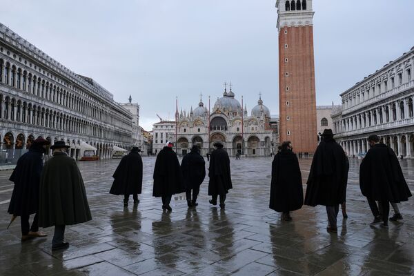 يتجمع الأشخاص الذين يرتدون تابارو التقليدي، وهو رداء أسود طويل، في ساحة سان مارك في اليوم الذي كان من المقرر أن يبدأ فيه كرنفال البندقية، مع إلغاء الحدث السنوي بسبب الاجراات الاحترازية المفروضة بسبب فيروس كورونا (كوفيد-19) في البندقية، إيطاليا، 31 يناير 2021. - سبوتنيك عربي