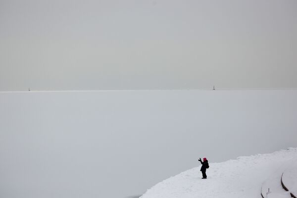 امرأة تلتقط صورة لبحيرة بالرب من وسط مدينة تشيكاغو، حيث شهدت أدنى درجات الحرارة منذ عقود، ولاية إلينوي، 09 فبراير 2021 - سبوتنيك عربي