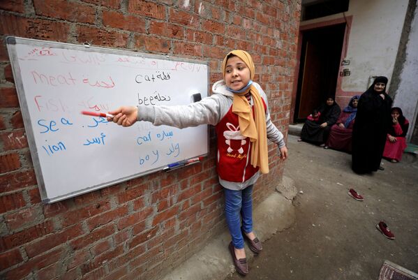 ريم الخولي، 12 عامًا، تعلم الأطفال في حيها حيث لاتزال المدارس مغلقة وسط جائحة فيروس كورونا (كوفيد-19)، في قرية إتميدة بمحافظة الدقهلية، مصر، 7 فبراير 2021 - سبوتنيك عربي