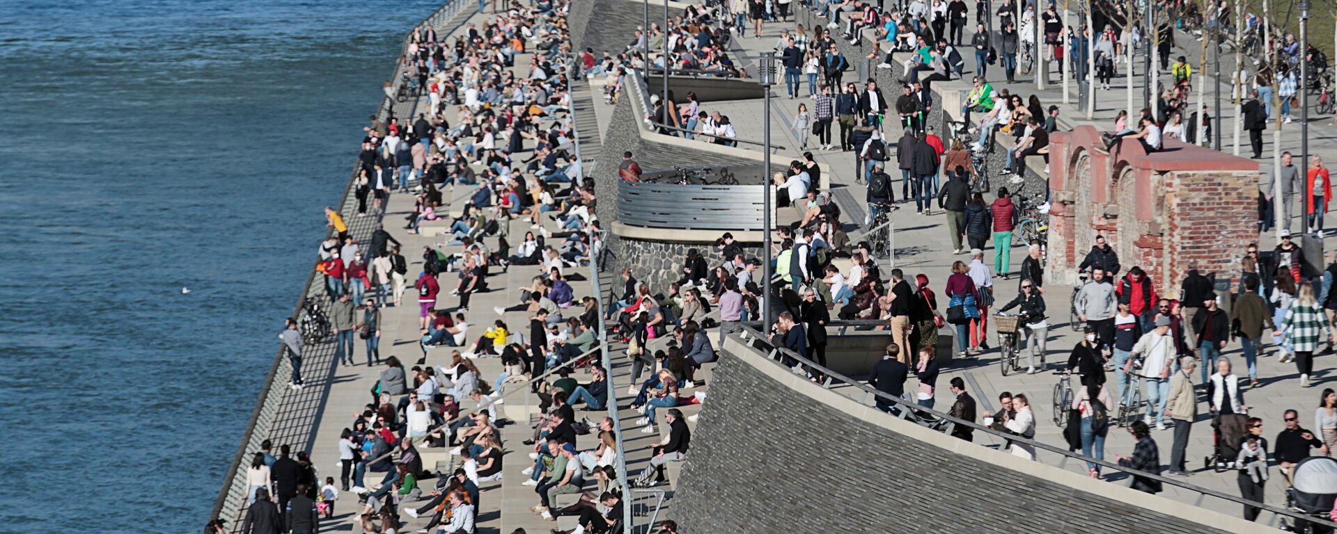 يقضي الناس وقتًا تحت أشعة الشمس على ضفاف نهر الراين وسط جائحة كورونا (كوفيد-19) في مدينة كولونيا في ألمانيا، 21 فبراير 2021. - سبوتنيك عربي, 1920, 25.05.2021