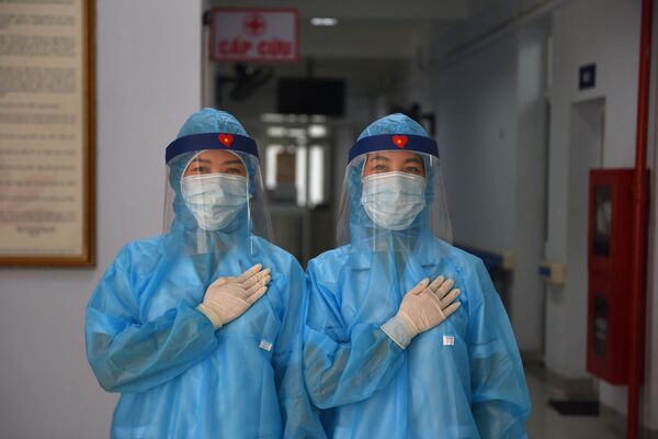 عمال الصحة يرتدون أزياء واقية يقفون لالتقاط صورة في مركز طبي مؤقت لاستقبال مرضى فيروس كورونا كوفيد-19 في هانوي، فيتنام 30 يوليو 2020 - سبوتنيك عربي