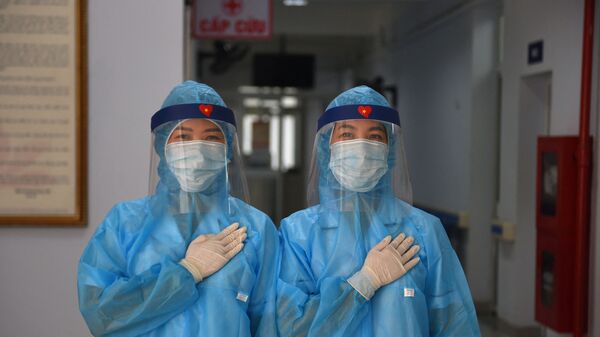 عمال الصحة يرتدون أزياء واقية يقفون لالتقاط صورة في مركز طبي مؤقت لاستقبال مرضى فيروس كورونا كوفيد-19 في هانوي، فيتنام 30 يوليو 2020 - سبوتنيك عربي