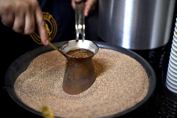 يقوم صانع القهوة المكسيكي بإعداد قهوة تركية مصنوعة داخل وعاء نحاسي على الرمال الساخنة أثناء افتتاح مهرجان القهوة إكسبو-كافيه 2017، بنسخته الـ 20 في مدينة مكسيكو سيتي، المكسيك،31 أغسطس 2017 - سبوتنيك عربي