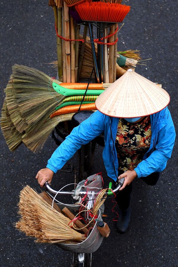 بائع متجول يحمل أعواد مكنسة على دراجته في أحد شوارع مدينة هانوي، فيتنام 18 مارس 2021 - سبوتنيك عربي
