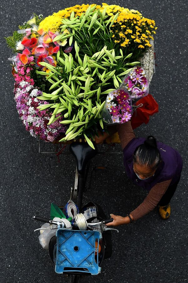 بائع متجول يحمل الأزهار على دراجته في أحد شوارع مدينة هانوي، فيتنام 18 مارس 2021 - سبوتنيك عربي
