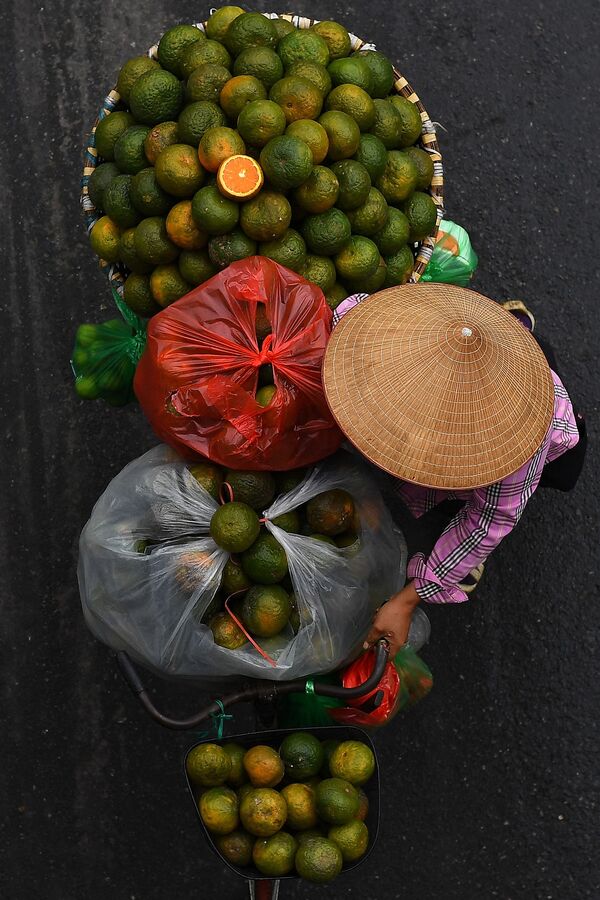 بائع متجول يحمل البرتقال على دراجته في أحد شوارع مدينة هانوي، فيتنام 18 مارس 2021 - سبوتنيك عربي