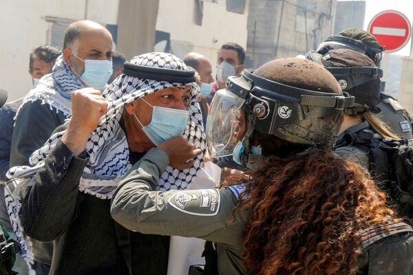 متظاهر فلسطيني يشتبك مع شرطية حدود إسرائيلية خلال مسيرة يوم الأرض، في سبسطية بالقرب من نابلس، في الضفة الغربية،  في 30 مارس 2021 - سبوتنيك عربي