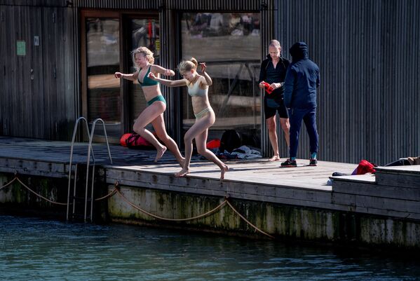امرأتان تقفزان إلى بركة مياه  في منطقة ساندكاز هافنباد المخصصة للسباحة والاستجمام  كوبنهاغن، الدنمارك 30 مارس 2021 - سبوتنيك عربي