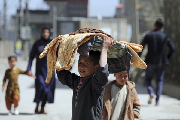 طفل أفغاني يحمل الخبز على رأسه في كابول، أفغانستان 29 مارس 2021 - سبوتنيك عربي