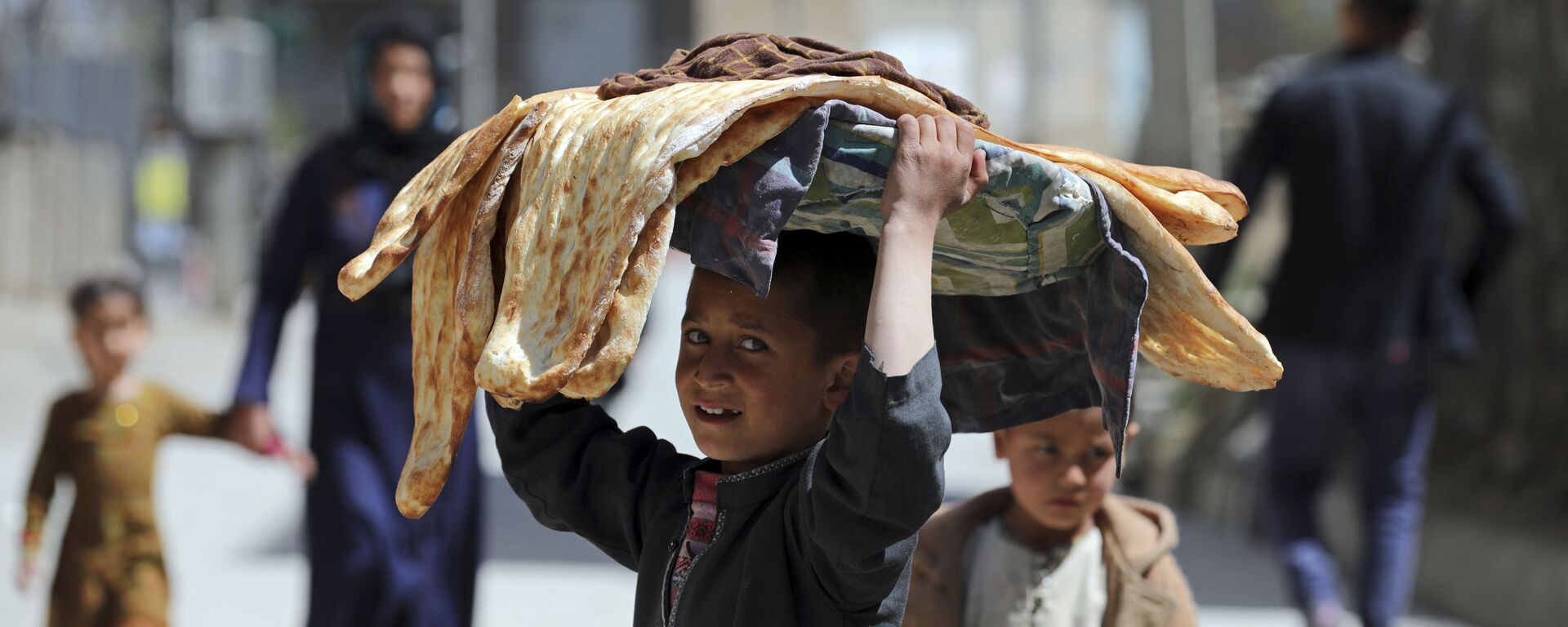 طفل أفغاني يحمل الخبز على رأسه في كابول، أفغانستان 29 مارس 2021 - سبوتنيك عربي, 1920, 04.06.2021