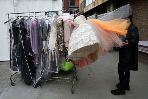 رجل يفرز تصميمام المصمم على علاقة ملابس خارج مكان لعرض الأزياء، ي إار أسبوع الموضة في بكين، الصين، 30 مارس 2021 - سبوتنيك عربي