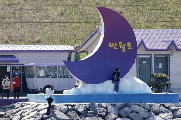 سياح يلتقطون صوراً على خلفية شعار الجزر البنفجسية في محافظة تشلا الجنوبية في كوريا الجنوبية، 6 أبريل 2021 - سبوتنيك عربي