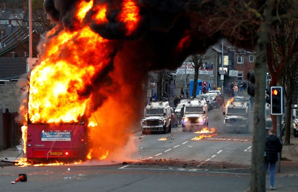 سيارات الشرطة تظهر خلف حافلة مخطوفة تحترق على طريق شانكيلЛ مع استمرار الاحتجاجات في بلفاست، أيرلندا الشمالية، 7 أبريل 2021 - سبوتنيك عربي