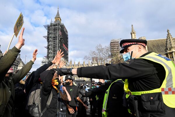 متظاهرون يرفعون أيديهم في وجوه ضباط الشرطة البريطانية خلال مظاهرة في لندن، بريطانيا، 3 أبريل / نيسان 2021 - سبوتنيك عربي