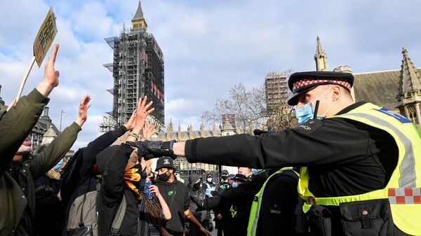 متظاهرون يرفعون أيديهم في وجوه ضباط الشرطة البريطانية خلال مظاهرة في لندن، بريطانيا، 3 أبريل / نيسان 2021 - سبوتنيك عربي