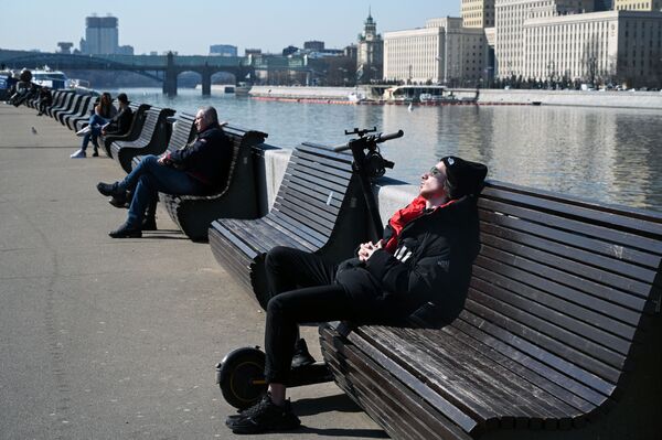 أشخاص يجلسون على مقاعد على ضفة نهر موسكو، روسيا 11 أبريل 2021 - سبوتنيك عربي