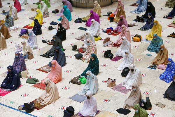 نساء ترتدي كمامات واقية وتتابعد اجتماعيا خلال صلاة التراويح الأولى في رمضان هذا العام في مسجد استقلال، إندونيسيا 12 أبريل 2021 - سبوتنيك عربي