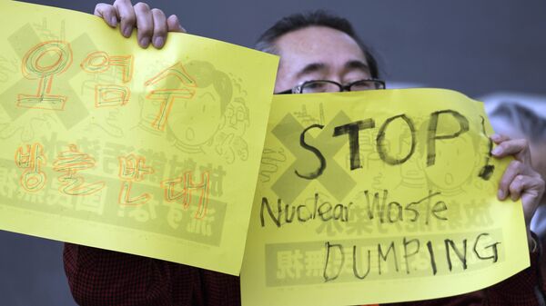 متظاهرون يرفعون لافتات احتجاجية على خطة الحكومة اليابانية لإطلاق أكثر من مليون طن من المياه المعالجة من محطة فوكوشيما النووية المنكوبة في المحيط، خارج مكتب رئيس الوزراء في طوكيو في 13 أبريل 2021 - سبوتنيك عربي