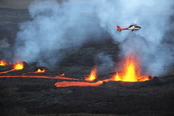 تُظهر هذه الصورة التي التقطت في 10 أبريل 2021 طائرة هليكوبتر تحلق فوق الحمم البركانية من بركان بيتون دي لا فورنيز، على الجانب الجنوبي من البركان، في جزيرة ريونيون الفرنسية في المحيط الهندي. - سبوتنيك عربي
