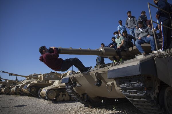 طلاب يصعدون على دبابة في إطار فعاليات الاحتفال بالذكرى السنوية لإحياء ذكرى الجنود القتلى وضحايا الإرهاب، في موقع نصب سلاح المدرعات في اللطرون، إسرائيل، 14 أبريل 2021 - سبوتنيك عربي
