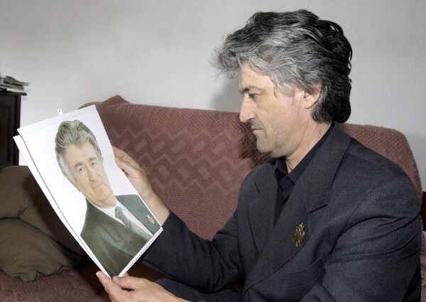 رجل يدعى بيتر سيكيتش ينظر إلى صورة شبيهه السياسي الصربي والرجل الملاحق من المحكمة الجنائية الدولية رادوفان كاراديتش، 2004 - سبوتنيك عربي