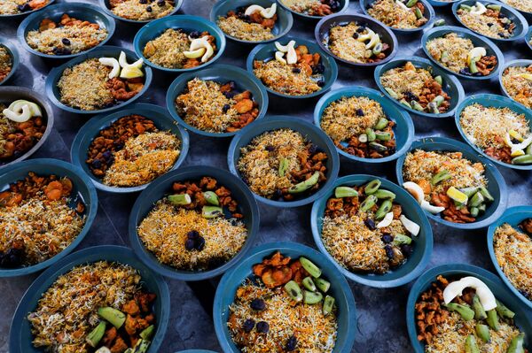 أواني من الأرز المطبوخ والفواكه جاهزة للتوزيع على الصائمين قبيل إفطار رمضان،  وسط اجراءات احترازية بسبب مرض فيروس كورونا (كوفيد-19) في كراتشي، باكستان، 17 أبريل 202 - سبوتنيك عربي