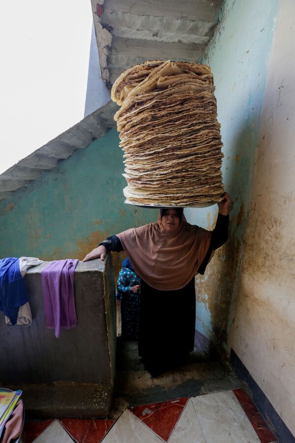 نور الصباح، 35 عامًا، تحمل الخبز على رأسها، تصعد اسلم منزلها، قبيل إفطار رمضان في بني سويف، مصر، 10 أبريل 2021 - سبوتنيك عربي