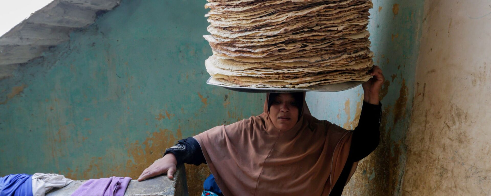 نور الصباح، 35 عامًا، تحمل الخبز على رأسها، تصعد اسلم منزلها، قبيل إفطار رمضان في بني سويف، مصر، 10 أبريل 2021 - سبوتنيك عربي, 1920, 07.04.2022