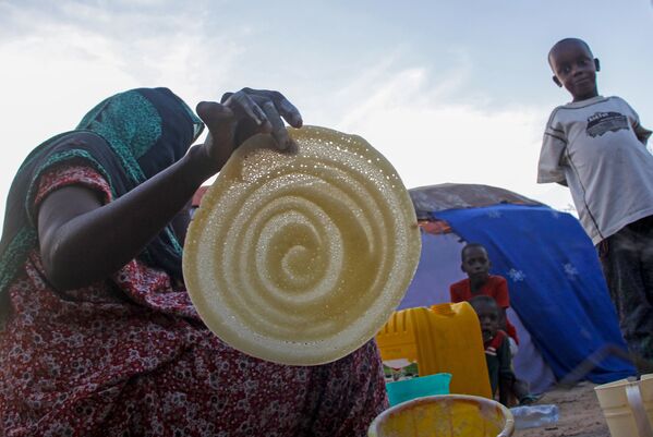 امرأة صومالية تصنع الفطائر لعائلتها في رمضان، في مخيم للنازحين في حي دار السلام بالعاصمة مقديشو، الصومال، 16 أبريل 2021 - سبوتنيك عربي