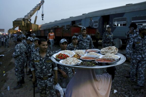 امرأة تجلب الطعام لقوات الأمن لتناول إفطار رمضان، في موقع قطار ركاب خرج عن مساره مما أدى إلى إصابة حوالي 100 شخص بالقرب من بنها بمحافظة القليوبية، مصر، 18 أبريل 2021. - سبوتنيك عربي