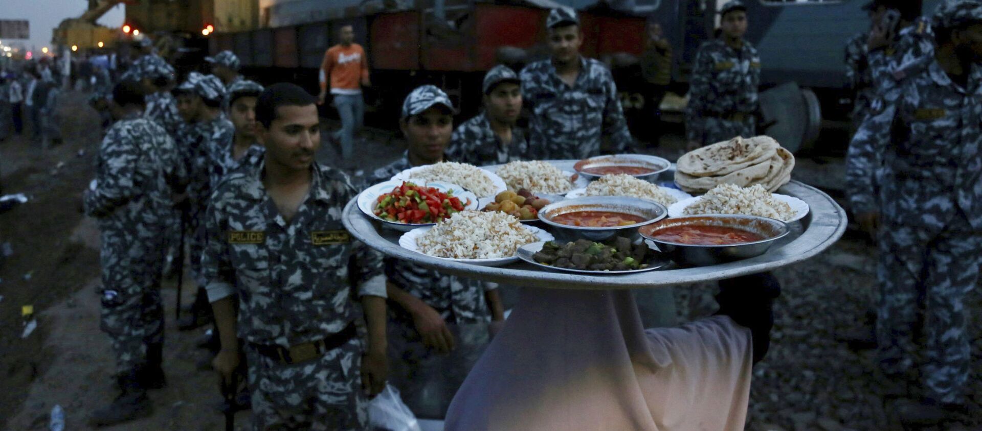 امرأة تجلب الطعام لقوات الأمن لتناول إفطار رمضان، في موقع قطار ركاب خرج عن مساره مما أدى إلى إصابة حوالي 100 شخص بالقرب من بنها بمحافظة القليوبية، مصر، 18 أبريل 2021. - سبوتنيك عربي, 1920, 24.04.2021