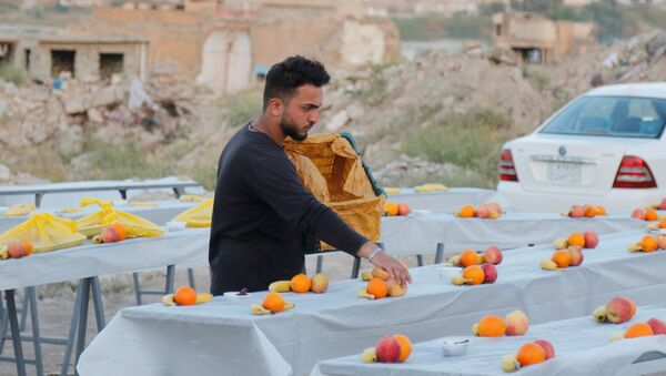 شاب يعد الطعام لوجبات الإفطار ويضع الفواكه على طاولة إفطار رمضان في الموصل، العراق، 15 أبريل 2021 - سبوتنيك عربي