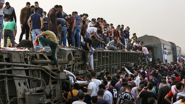 تجمع الناس حول قطار في موقع حادث سكة حديد في مدينة طوخ في محافظة القليوبية، وسط دلتا النيل في مصر، 18 أبريل 2021 - سبوتنيك عربي