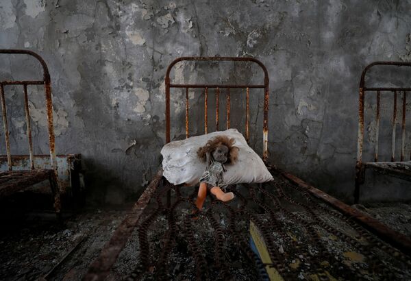 دمية قديمة وضعها زائر، شوهدت على سرير في روضة أطفال بالقرب من محطة تشيرنوبيل للطاقة النووية في مدينة بريبيات المهجورة (في ذكرى كارثة تشيرنوبيل)، أوكرانيا، 12 أبريل 2021 - سبوتنيك عربي