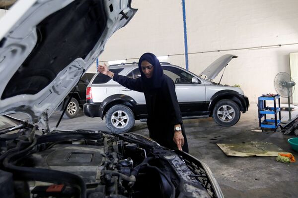 الإماراتية هدى المطروشي، 36 عاماً، تقوم بتصليح سيارة في كراجها في الشارقة، الإمارات العربية المتحدة، 21 أبريل 2021 - سبوتنيك عربي