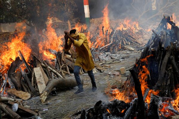 رجل يسير بجوار موقع لحرق جثث ضحايا كورونا، إثر تسجيل أرقام قياسية لحالات الإصابة بمرض كوفيد-19 وعدم توفر ثلاجات ومقابر تكفي الأموات، في نيودلهي، الهند 26 أبريل 2021 - سبوتنيك عربي