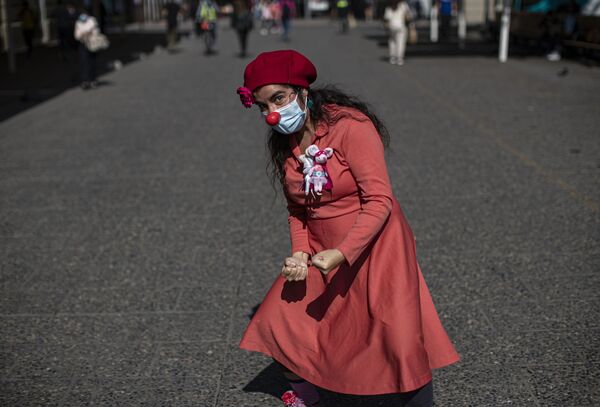 مهرجة تدعى لوريتو رايويلا، تقف لالتقاط صورة خلال مسيرة الأنوف الحمراء نظمتها مجموعة المهرجين فلاينغ لافتر وسط جائحة فيروس كورونا في مدينة سانتياغو، تشيلي، 28 أبريل 2021 - سبوتنيك عربي