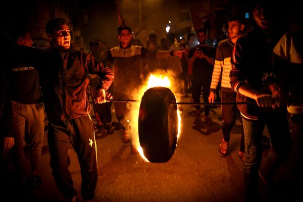 فلسطينيون يحرقون إطارًا مرددين إشعارات مؤيدة للمسجد الأقصى خلال تجمع حاشد في مدينة غزة، قطاع غزة، فلسطين 24 أبريل 2021. - سبوتنيك عربي