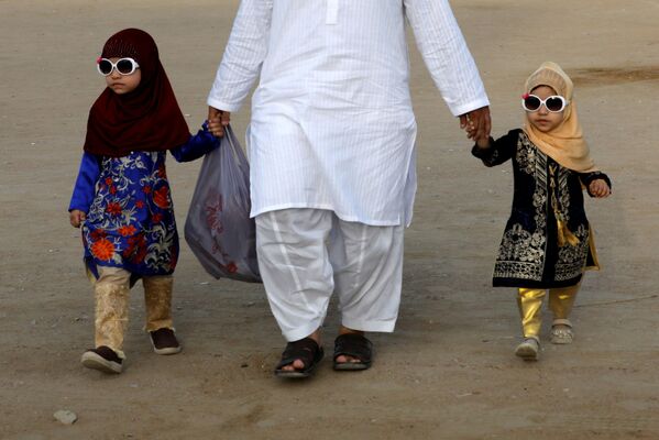أب مع طفليه بعد صلاة عيد الفطر في مدينة كاراتشي، باكستان 13 مايو 2021 - سبوتنيك عربي