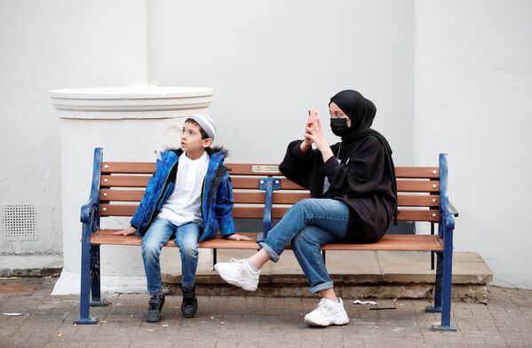 الصبي، موسى خان، والفتاة، تبارك خان، يجلسان قرب مسجد بعد صلاة عيد الفطر في سانت ألبانز، بريطانيا 11 مايو 2021 - سبوتنيك عربي