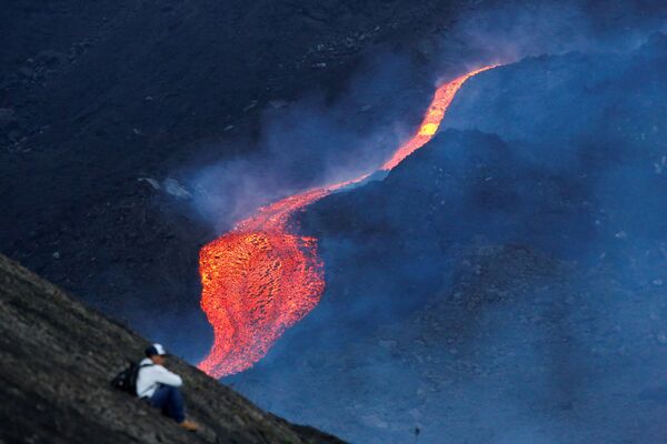  رجل يشاهد تدفق الحمم الساخنة من بركان باكايا في منطقة إسكوينتلا، غواتيمالا 8 مايو 2021 - سبوتنيك عربي