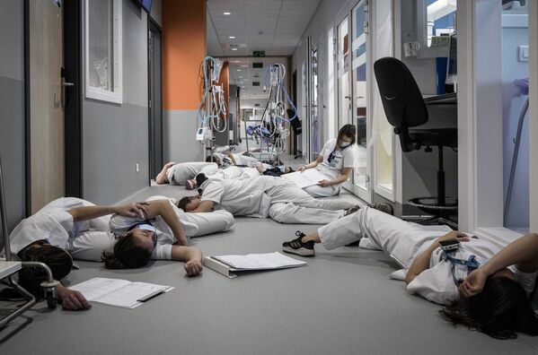 طاقم التمريض ينامون على الأرضية في وحدة العناية المركزة خلال عرض توضيحي في يوم التمريض والعناية الدولي في مستشفى مونت ليجيا في لييج، بلجيكا 12 مايو 2021 - سبوتنيك عربي