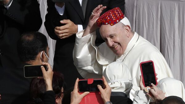 بابا الفاتيكان فرانسيس يبتسم بعد أن وضع أحد الحضور قبعة على رأسه في ساحة القديس داماسو بالفاتيكان أمام جمهوره الأسبوعي، 12 مايو 2021. - سبوتنيك عربي